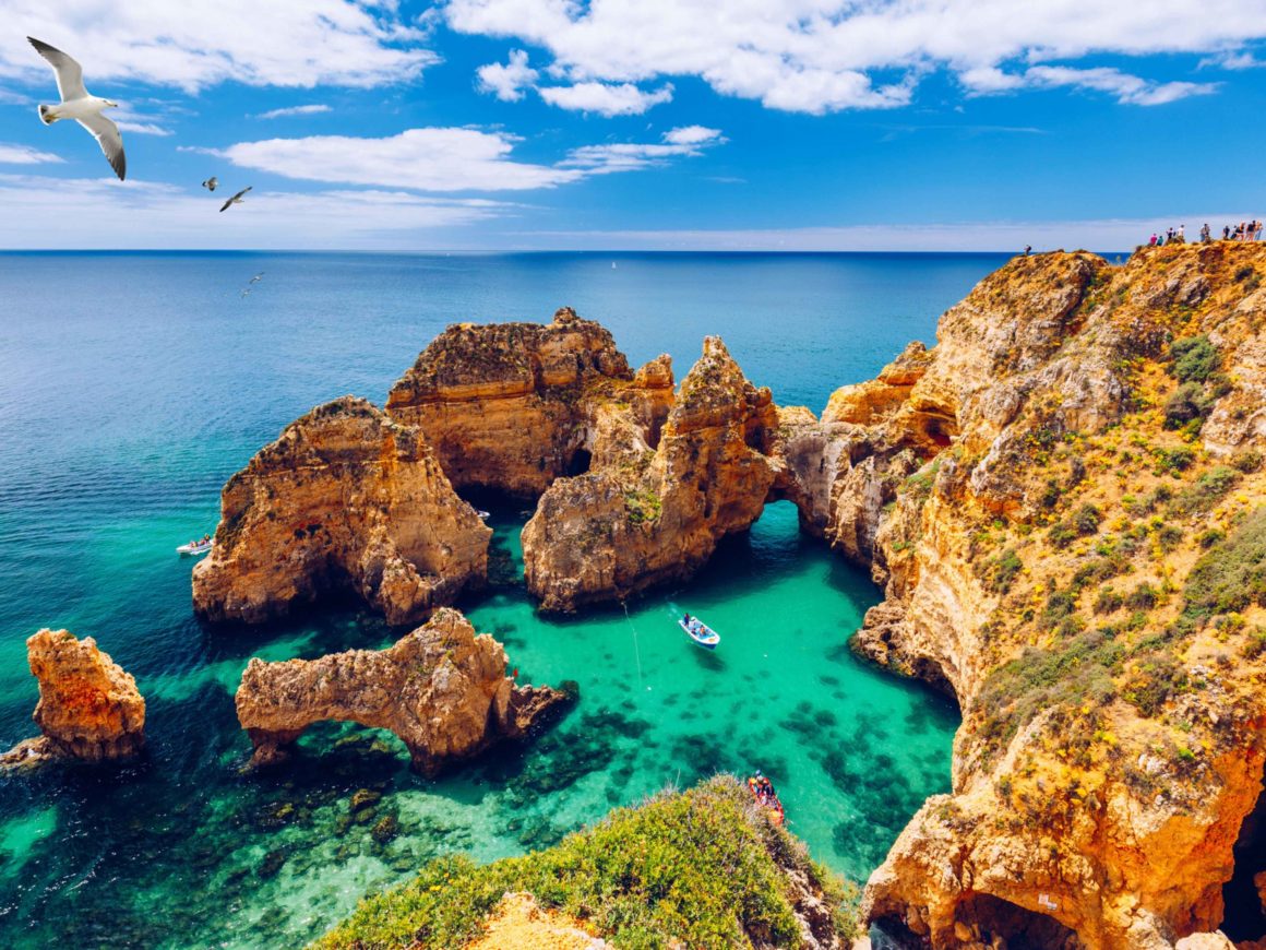 Panoramisch uitzicht, Ponta da Piedade met zeemeeuwen die over rotsen vliegen nabij Lagos in Algarve, Portugal. Klifrotsen, zeemeeuwen en toeristenboot op zee bij Ponta da Piedade, Algarve-regio, Portugal.
Ideale leuke vakantie bestemming.
