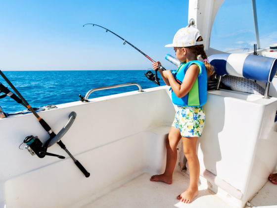 маленькая девочка рыбачит на яхте