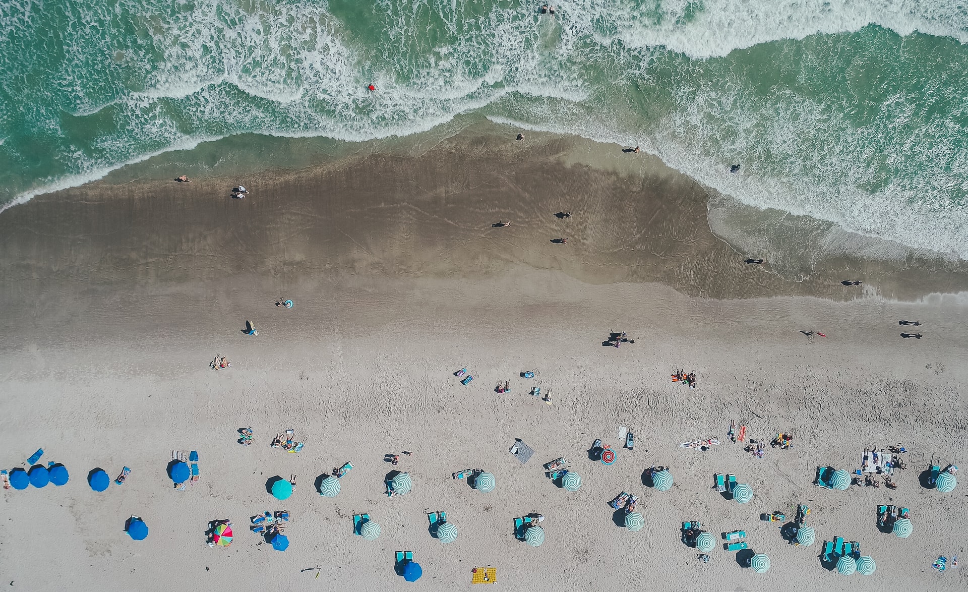 cocoa beach viewed from above with lots of parasols and waves