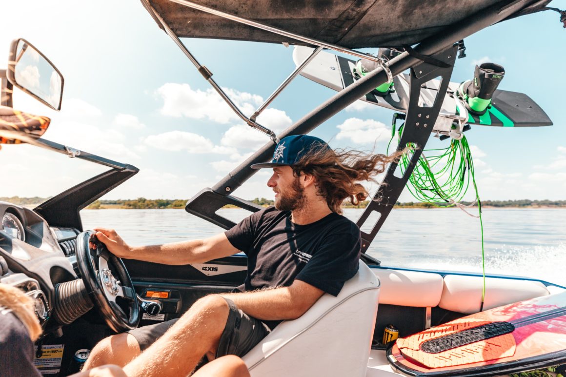 Man driving a motorboat with wakeboards attached