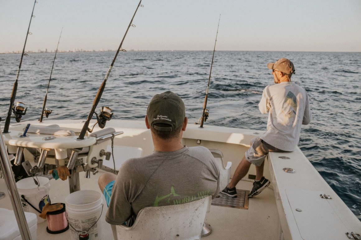 Two people fishing on a boat with fishing rods