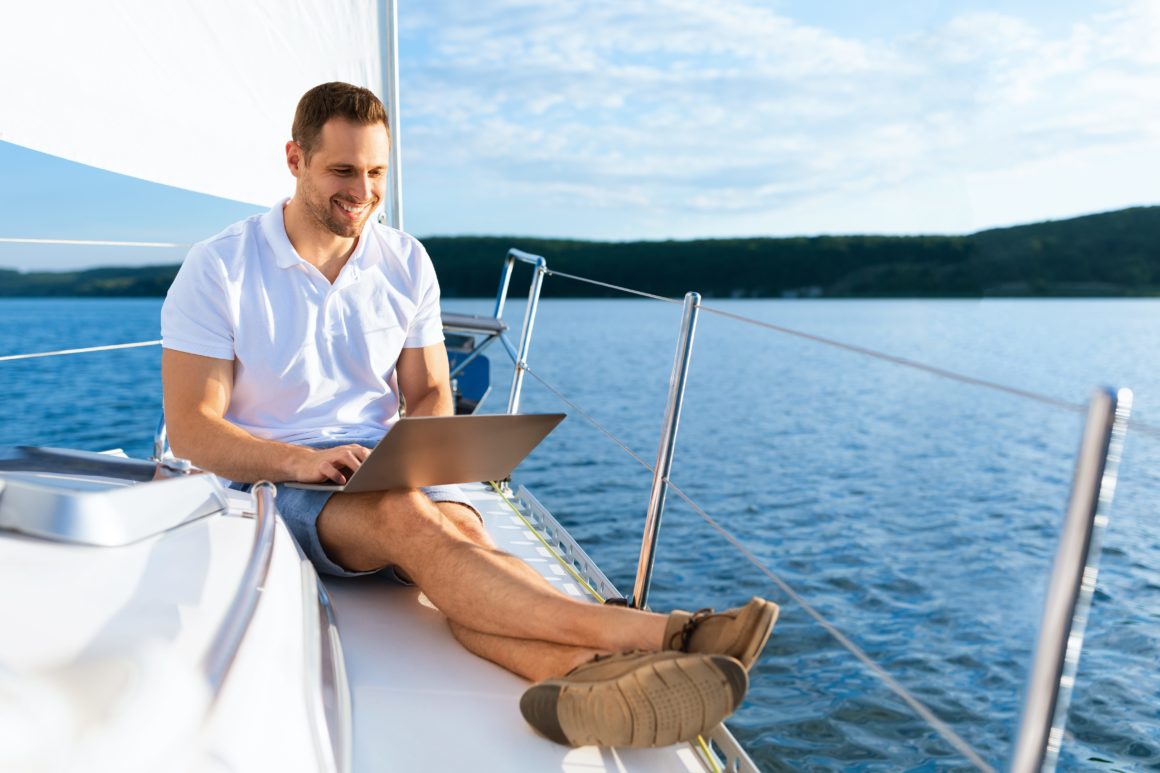 Man using laptop while sitting on boat deck