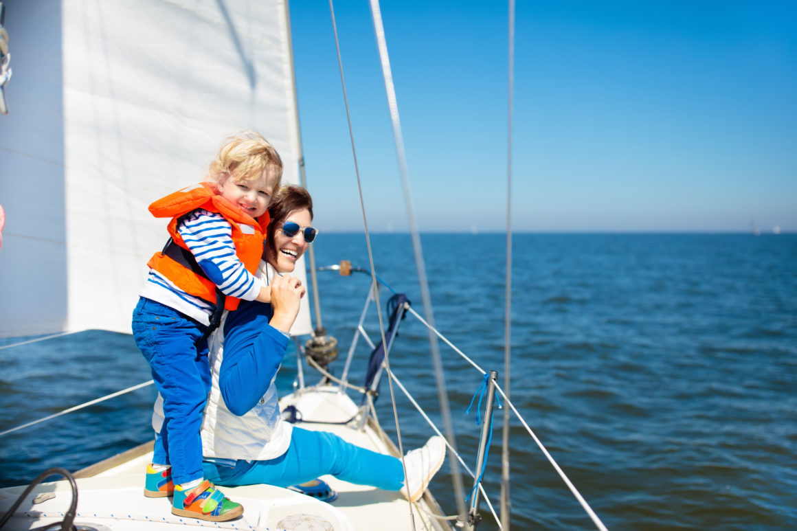 Kid with lifevest on a sailing trip with theirmom