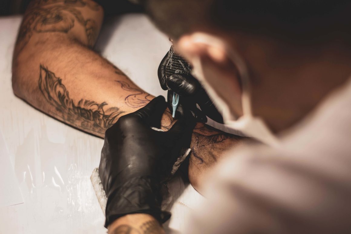man tattooing a forearm with nautical tattoos