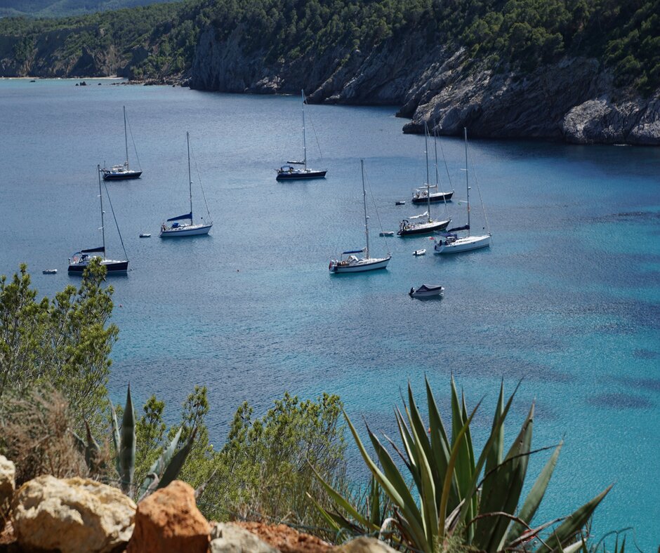 Photo capturing boats moored in a bay in Ibiza, with or without a boat license
