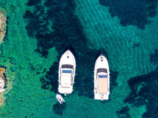 Areal view of boats next to a shore in turquoise green waters
