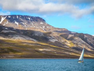 A sailboat in front of a mountain in a Nordic country