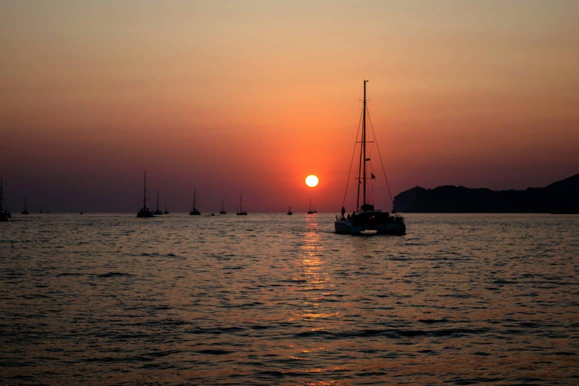 Un catamaran mouillant face au coucher de solel