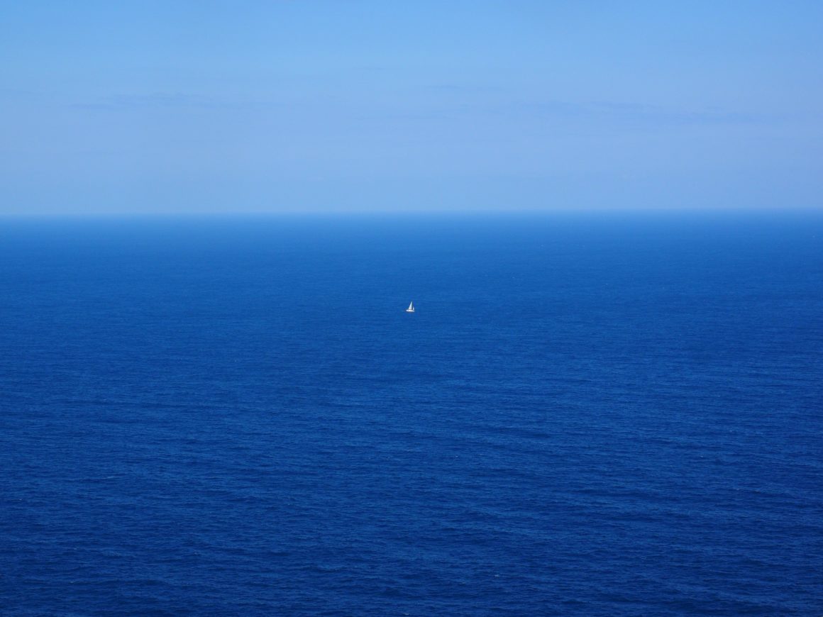 Petit voilier isolé au milieu d’un vaste océan bleu