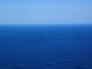 Petit voilier isolé au milieu d’un vaste océan bleu
