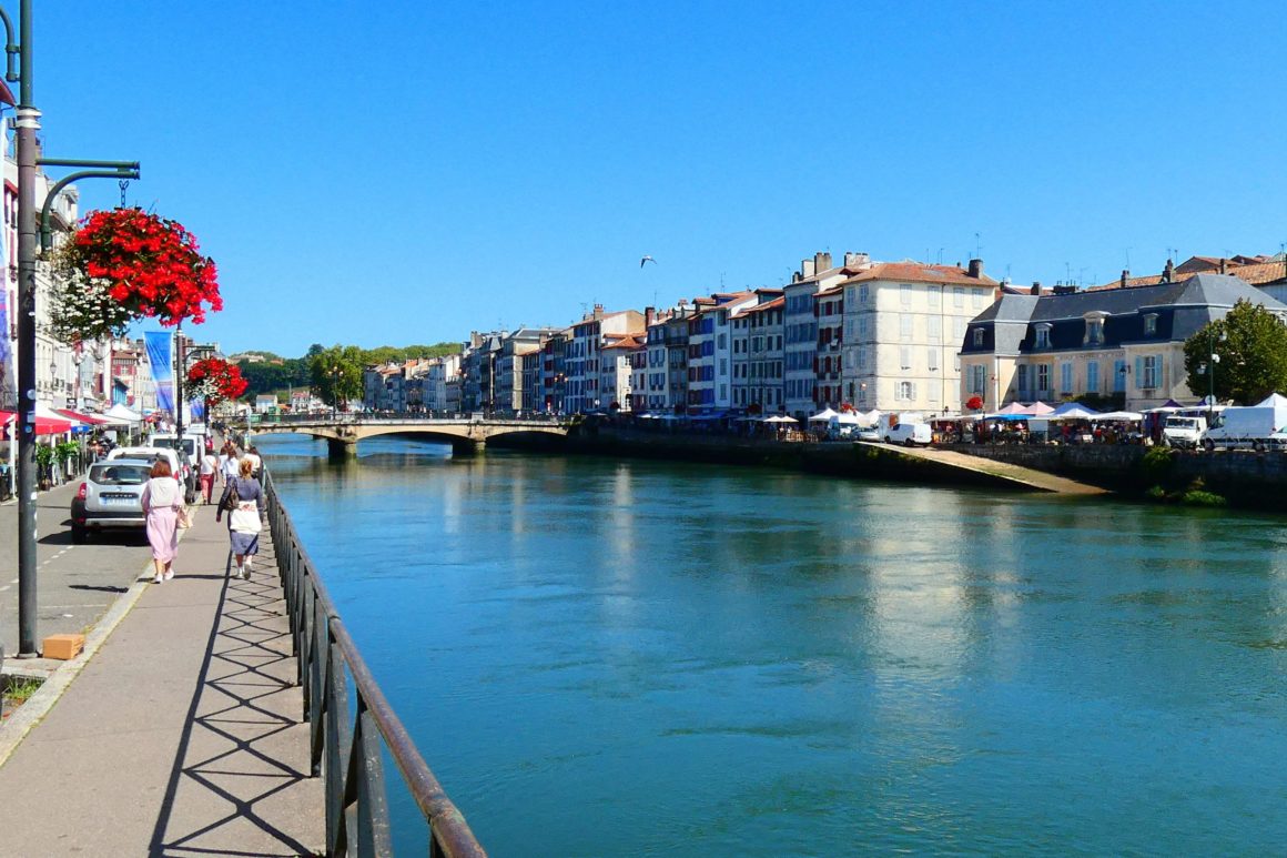 Quais ensoleillés de l'Adour à Bayonne avec architecture basque colorée.