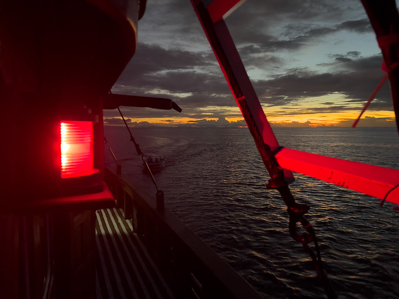 Feu de navigation rouge à bâbord visible sur le côté d’un bateau au coucher du soleil.