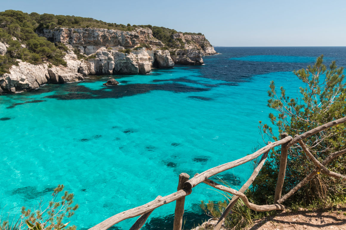 Cala Macarella, crique turquoise bordée de falaises claires et pins.