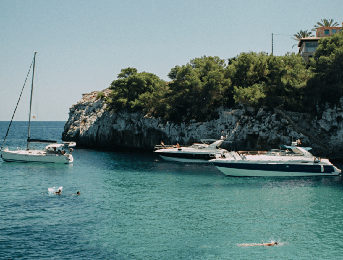 Voiliers et bateaux à moteur au mouillage dans une crique turquoise à Majorque.
