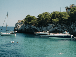 Voiliers et bateaux à moteur au mouillage dans une crique turquoise à Majorque.