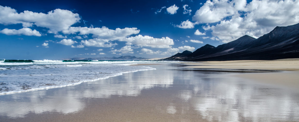 Immense plage de Cofete bordée par l’océan et des montagnes