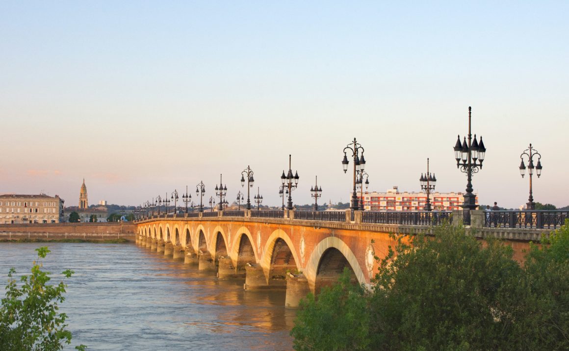 Le Pont de Pierre à Bordeaux traversant la Garonne au crépuscule.