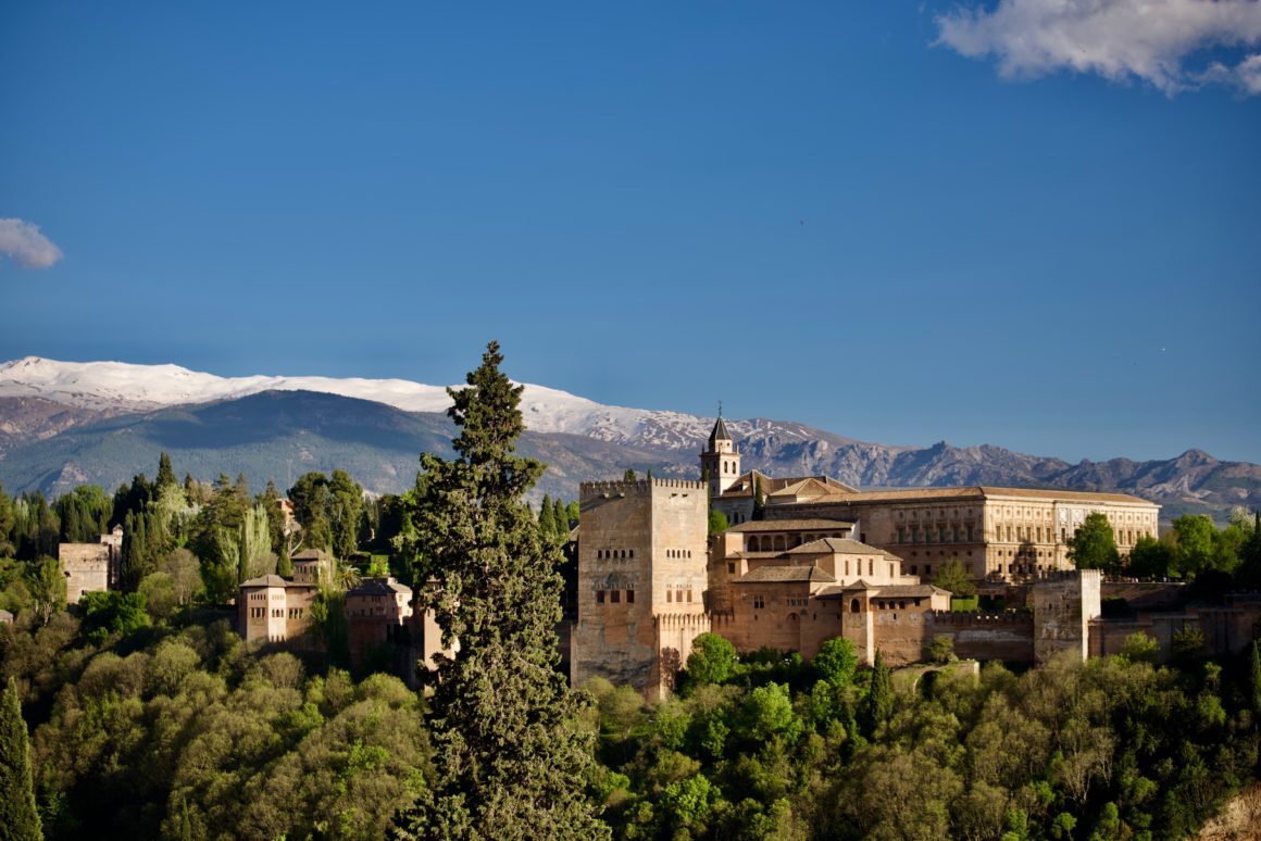Le palais de l'Alhambra à Grenade avec les montagnes enneigées de la Sierra Nevada en arrière-plan.