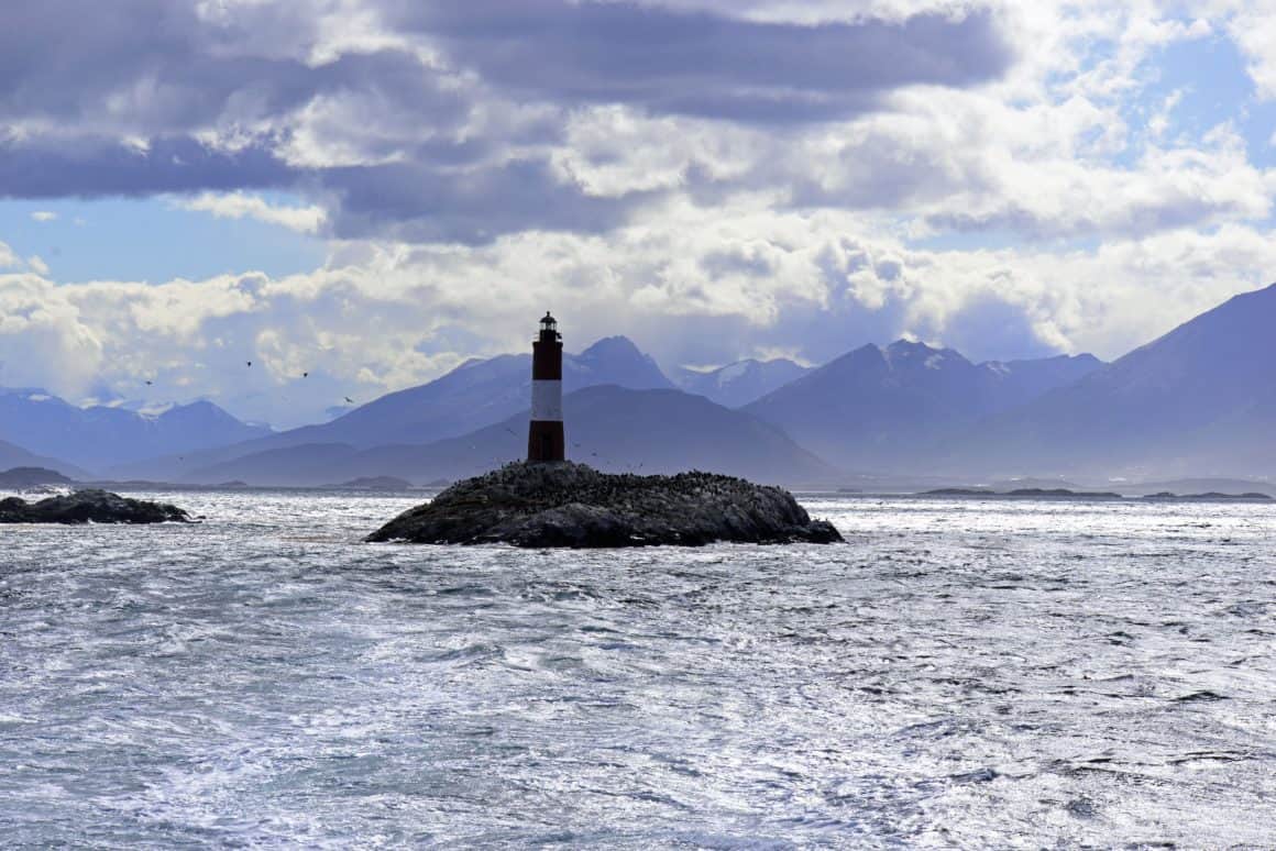 Phare Les Éclaireurs sur un îlot rocheux entouré de montagnes en Terre de Feu.