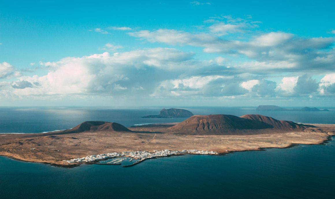 Vue aérienne de La Graciosa, île volcanique au nord de Lanzarote, avec village blanc et marina.