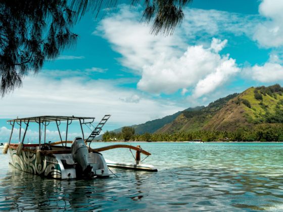 Bateau au mouillage dans un lagon turquoise face à une montagne verdoyante.