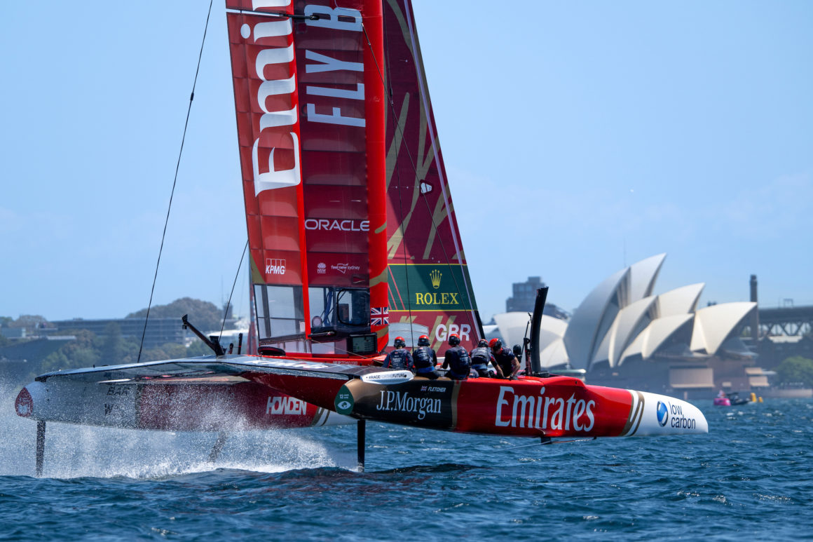 Catamaran de compétition Emirates Team New Zealand volant sur ses foils devant l'Opéra de Sydney.