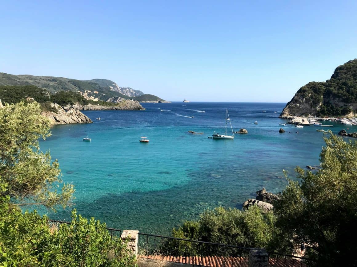 Bateaux et voilier au mouillage dans une baie calme de Corfou.